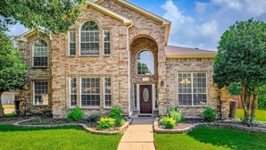 A two-story brick house with a central entrance, large windows, and a well-maintained lawn. - Secluded Luxe Home | Private Pool & Grill (Allen)