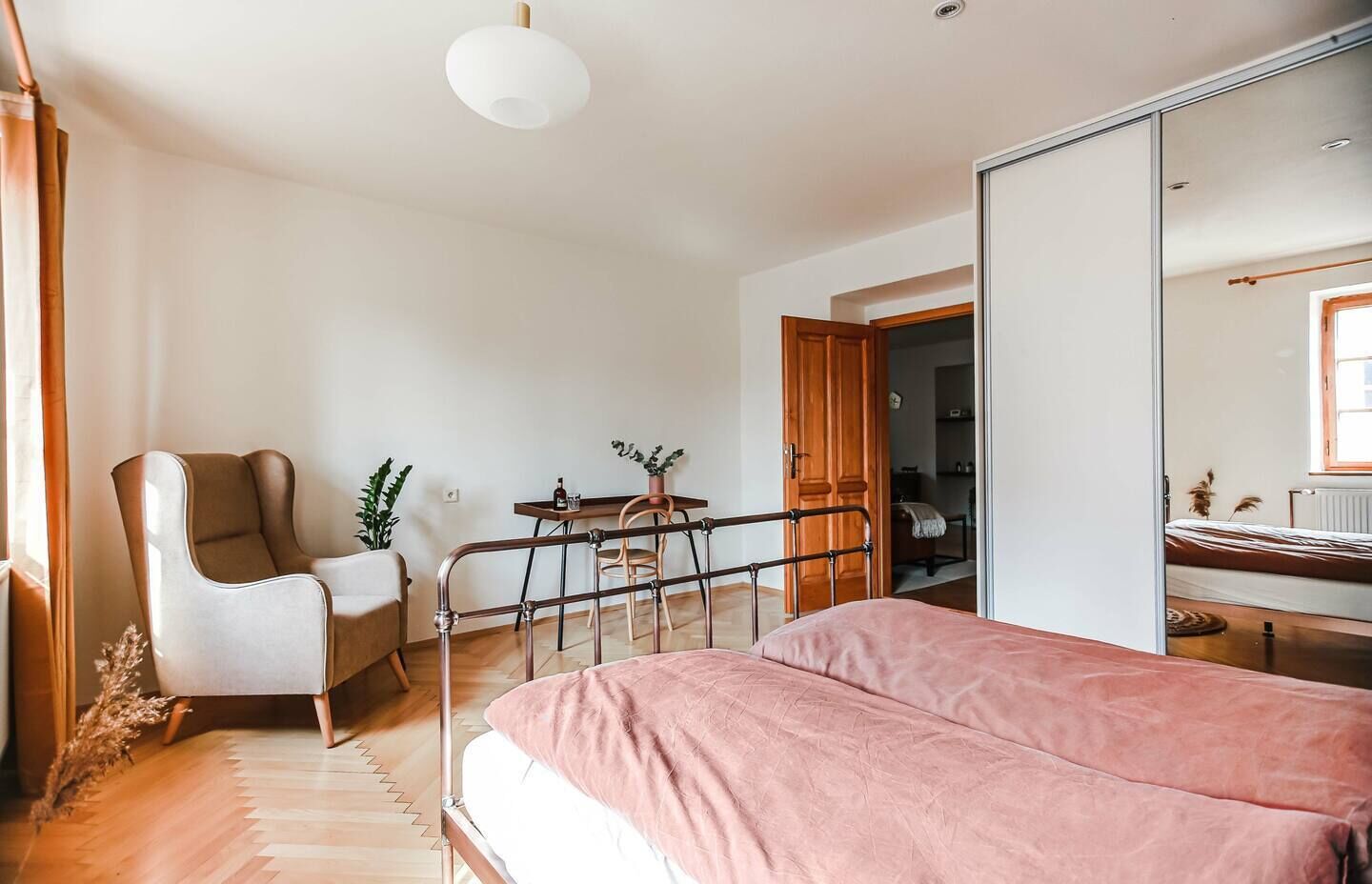Une chambre à coucher avec un lit, une chaise, un bureau et un miroir.