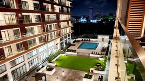 A modern hotel courtyard with a swimming pool, outdoor seating, and a well-maintained lawn. - Immaculate Beauty Gem-5 Star Location- Pools - Gym (Accra)