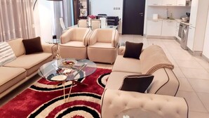 A modern living room with a sofa set, a glass coffee table, and a red and black patterned rug. - Immaculate Beauty Gem-5 Star Location- Pools - Gym (Accra)
