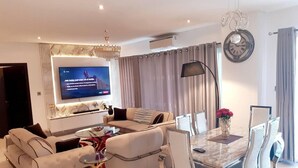 A modern living room with a sofa, a coffee table, and a dining area with chairs and a table. - Immaculate Beauty Gem-5 Star Location- Pools - Gym (Accra)