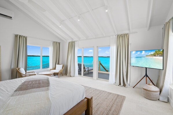 Ein Schlafzimmer mit einem großen Bett, einem Fernseher und Meerblick.