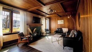 Un salon chaleureux avec une cheminée, des canapés en cuir et des boiseries.