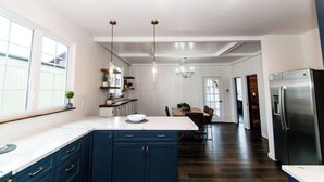 Une cuisine moderne avec des meubles de couleur bleu foncé, un plan de travail blanc et un réfrigérateur en acier inoxydable.