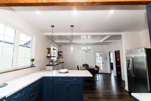 Una cucina moderna con mobili blu scuro, un piano di lavoro bianco e un frigorifero in acciaio inossidabile.