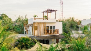 A modern, multi-story building with a wooden deck and a thatched roof structure. - Luna Rossa  Beach Villas (Sipacate)
