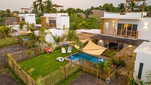 A resort with multiple white buildings, a swimming pool, and a fenced garden area. - Luna Rossa  Beach Villas (Sipacate)