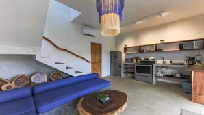 A modern kitchen with built-in appliances, a blue sofa, and a unique staircase design. - Luna Rossa  Beach Villas (Sipacate)