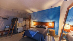 A bedroom with a large bed, a smaller bed, a ladder, a wooden headboard, a nightstand, and a hanging light fixture. - Luna Rossa  Beach Villas (Sipacate)