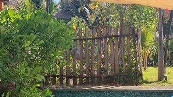A child playing in a pool surrounded by lush greenery and a wooden fence.