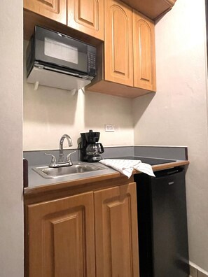 A compact kitchen with wooden cabinets, a microwave, a coffee maker, and a dishwasher. - #26 Beach Apartment 2br, 3ba w/ jet tub (Isabela)