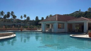 A clear blue swimming pool with a covered area and palm trees in the background. - #26 Beach Apartment 2br, 3ba w/ jet tub (Isabela)