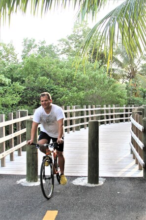Una persona in bicicletta su un ponte di legno con ringhiere, immersa nel verde.