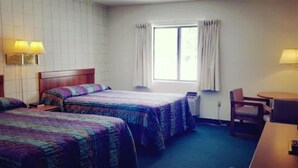 A hotel room with two beds, a desk, a chair, a window with curtains, and a wall-mounted lamp. - Oakridge Motel (Newaygo)