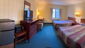 A hotel room with two beds, a desk with a refrigerator and microwave, a TV, and a window with curtains. - Oakridge Motel (Newaygo)