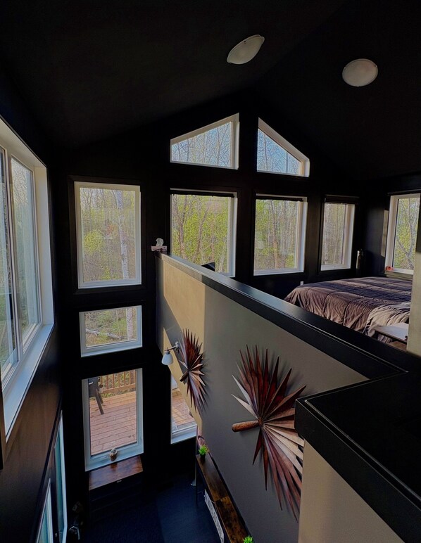 Ein Schlafzimmer mit mehreren Fenstern, einem Bett und Blick ins Freie.