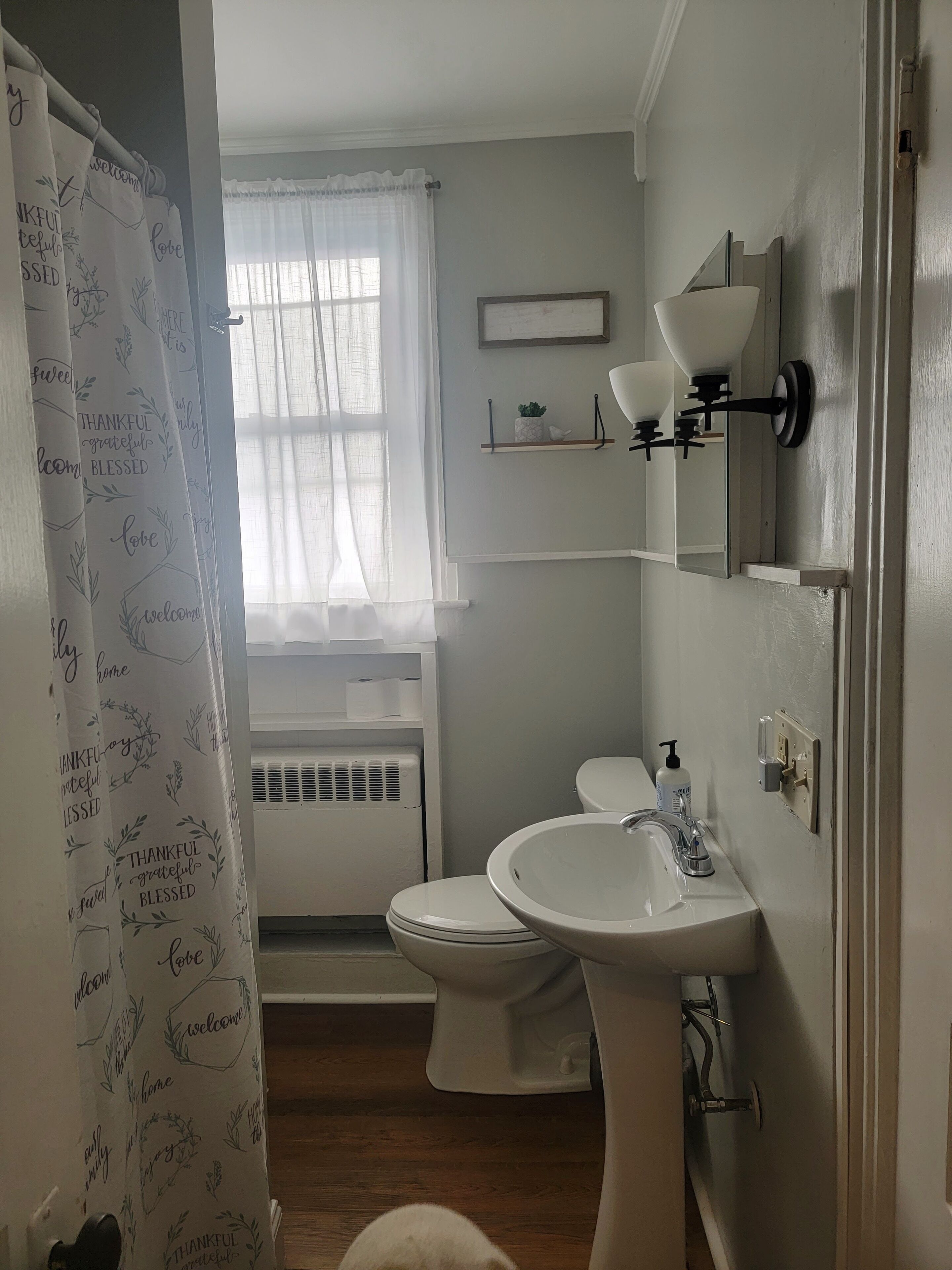 Een badkamer met een wit wastafelmeubel, toilet en douchegordijn met motiverende teksten.