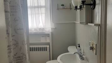 Een badkamer met een wit wastafelmeubel, toilet en douchegordijn met motiverende teksten.