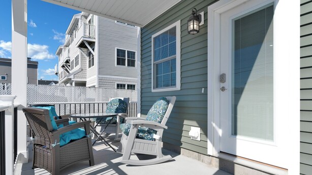 A covered porch with wicker furniture and a rocking chair. - Across the street from the beach with EV Charger.  Unit A in Duplex (Old Orchard Beach)