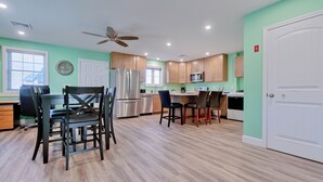 A modern kitchen with wooden cabinets, stainless steel appliances, and a dining area with chairs and a table. - Across the street from the beach with EV Charger.  Unit A in Duplex (Old Orchard Beach)