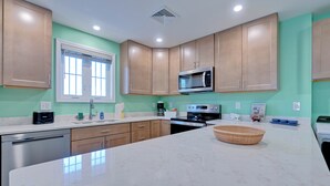 A modern kitchen with wooden cabinets, a stainless steel microwave, and a large marble countertop. - Across the street from the beach with EV Charger.  Unit A in Duplex (Old Orchard Beach)