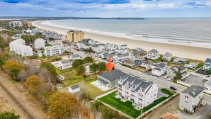An aerial view of a coastal residential area with houses, a beach, and a road. - Across the street from the beach with EV Charger.  Unit A in Duplex (Old Orchard Beach)