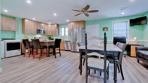 A modern kitchen with wooden cabinets, stainless steel appliances, and a dining area with a table and chairs.