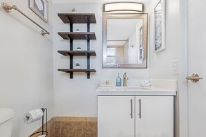 A bathroom with a white sink, a mirror with a decorative frame, a towel rack, and a toilet.
