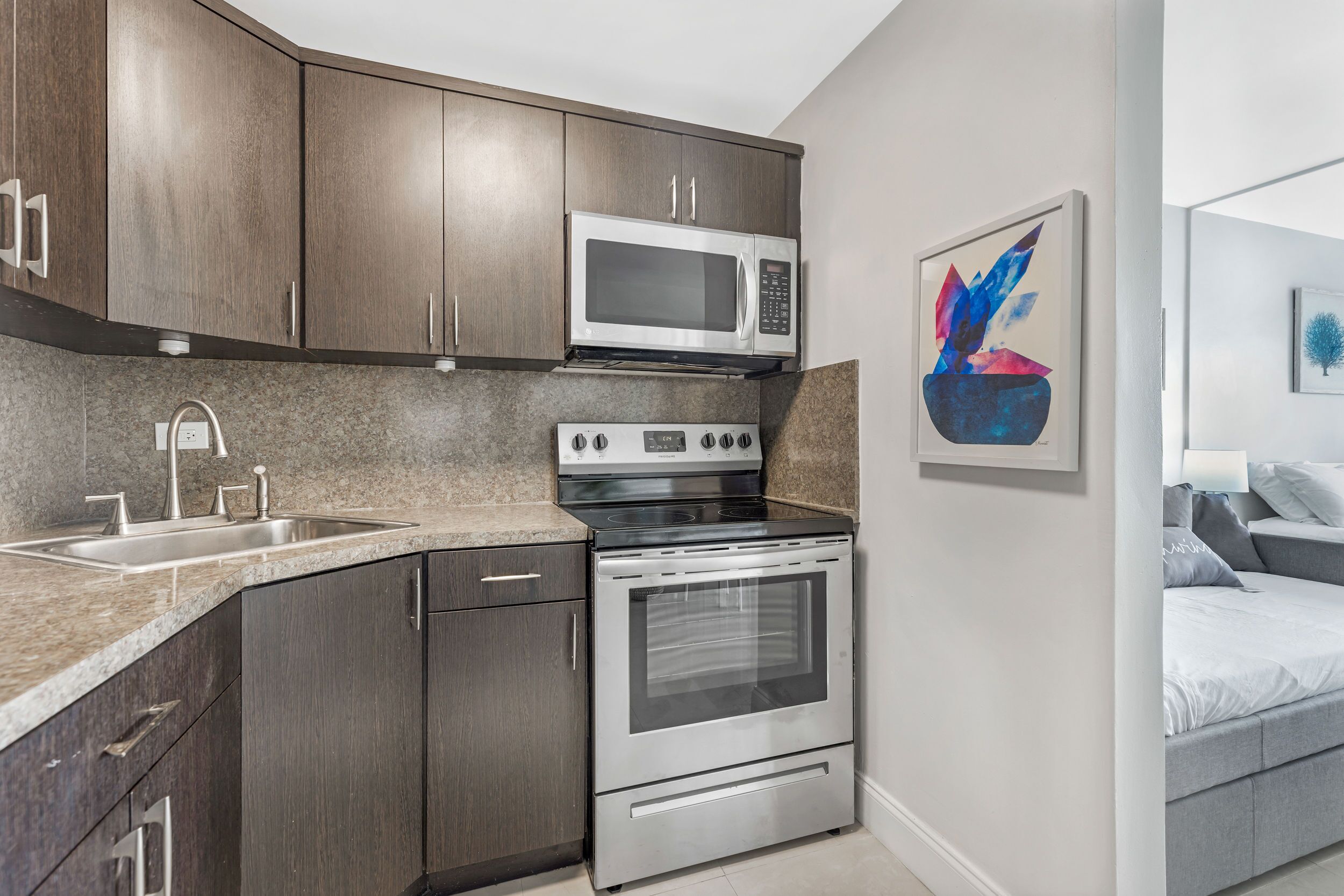 A modern kitchen with dark wood cabinets, a stainless steel microwave, stove, and dishwasher.