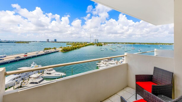 A balcony with a view of a marina, boats, and distant cityscape. - Waterfront condo Studio - Free Parking (North Bay Village)