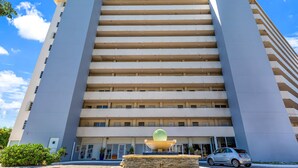 A multi-story hotel with a central fountain, a clear blue sky, and a parked car. - Waterfront condo Studio - Free Parking (North Bay Village)