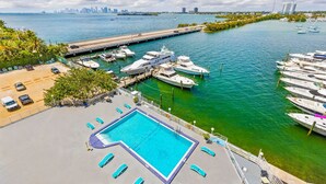 A marina with boats docked, a swimming pool, and a city skyline in the background. - Waterfront condo Studio - Free Parking (North Bay Village)