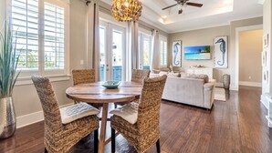A spacious living area with a dining table, wicker chairs, a sofa, and a ceiling fan. - TaDa! - Heated Pool and Golf Cart! (Santa Rosa Beach)