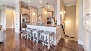 A modern kitchen with a central island, bar stools, stainless steel appliances, and pendant lighting. - TaDa! - Heated Pool and Golf Cart! (Santa Rosa Beach)