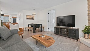 Ein modernes Wohnzimmer mit Sofa, Couchtisch, Fernseher und Essbereich.