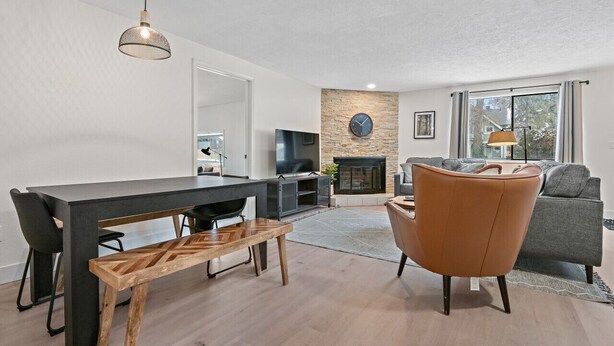 Ein modernes Wohnzimmer mit Esstisch, einer Couch, einem Kamin und einem Fernseher.