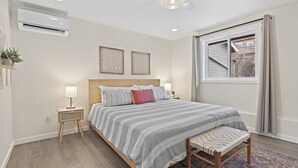 A bedroom with a bed, bedside tables, a window, and an air conditioning unit. - Upscale Rockwood Boho Townhouse (Spokane)