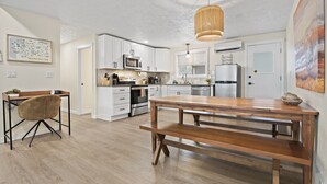 A modern kitchen with white cabinets, stainless steel appliances, and a wooden dining table. - Upscale Rockwood Boho Townhouse (Spokane)