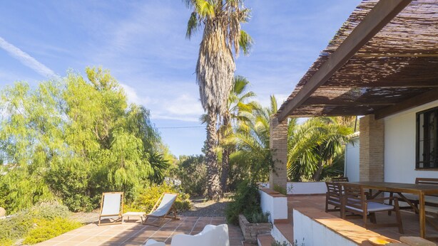 A patio with white plastic chairs, a wooden table, and a pergola. - Cubo's La Maison de Mily / fireplace / private pool / free wifi (Coín)