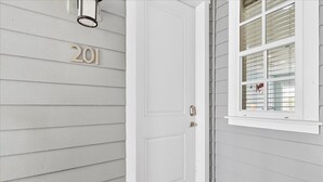 A white door with a number '201' above it, a window with blinds, and a small porch area. - South Pier TC 3201 (Port Aransas)
