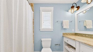 A bathroom with a toilet, a window, a towel rack, and a mirror. - South Pier TC 3201 (Port Aransas)