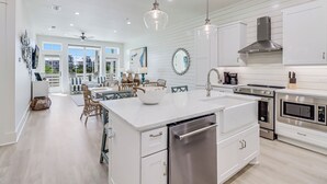 A modern kitchen with white cabinetry, stainless steel appliances, and a central island. - Beach Craft TC 8202 (Port Aransas)