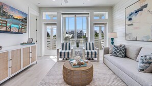 A spacious living room with a large window, a ceiling fan, and a view of the outside. - Beach Craft TC 8202 (Port Aransas)