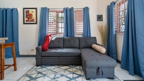 A living room with a grey sectional sofa, a small wooden table, and a patterned rug. - Shaw Park Gem (Ocho Rios)