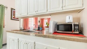A kitchen with white cabinets, a microwave, a toaster, and a sink. - Shaw Park Gem (Ocho Rios)