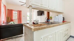 A kitchen with white cabinets, a countertop, and a sink. - Shaw Park Gem (Ocho Rios)