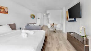 Moderni hotellihuone, jossa on suuri sänky, työpöytä, televisio ja ruokailutila.