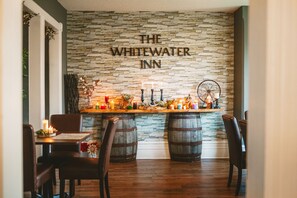 A restaurant with a stone wall, wooden barrels, and a sign reading "The Whitewater Inn". - The Whitewater Inn (Whitewater Region)