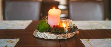 A candle on a table with moss and a glass candle holder.