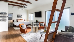 A modern bedroom with a large bed, a desk, and a chair. There is a ladder in the room, and a TV mounted on the wall. - Walk to the waterfront The South Sound  (Tacoma)